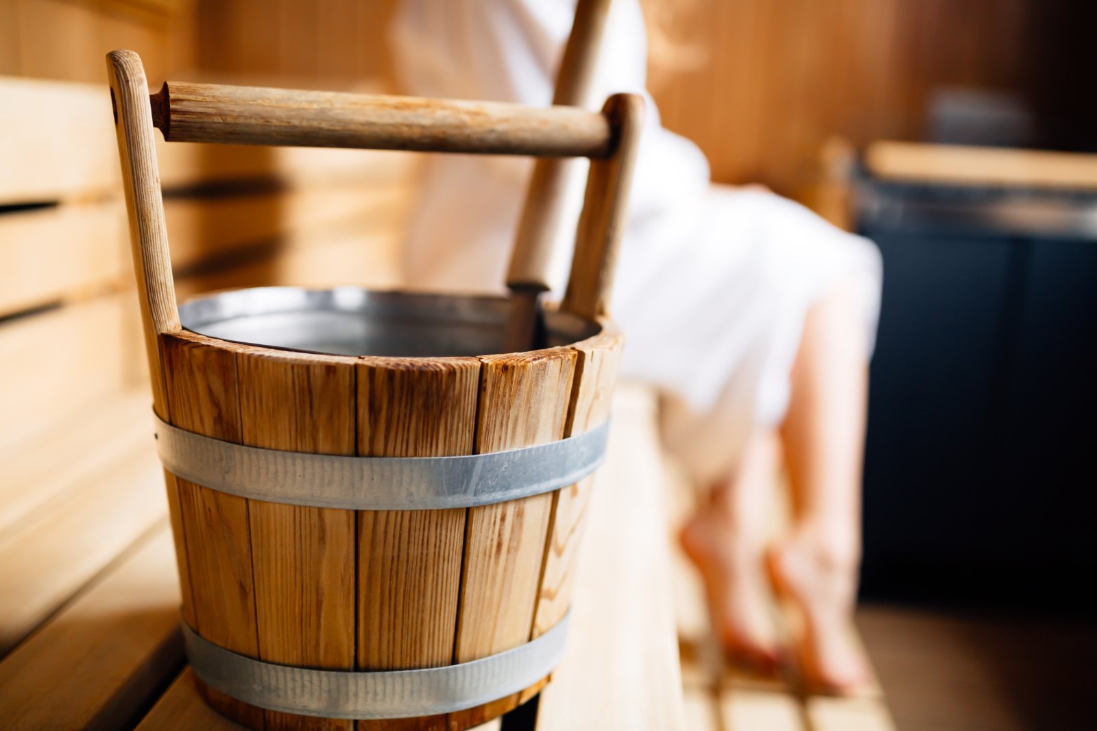 Detailaufnahme aus dem Saunabereich des Die Gams Hotel Resort in Bad Hindelang mit traditionellem Aufgusskübel aus Holz und entspannter Wellnessatmosphäre.