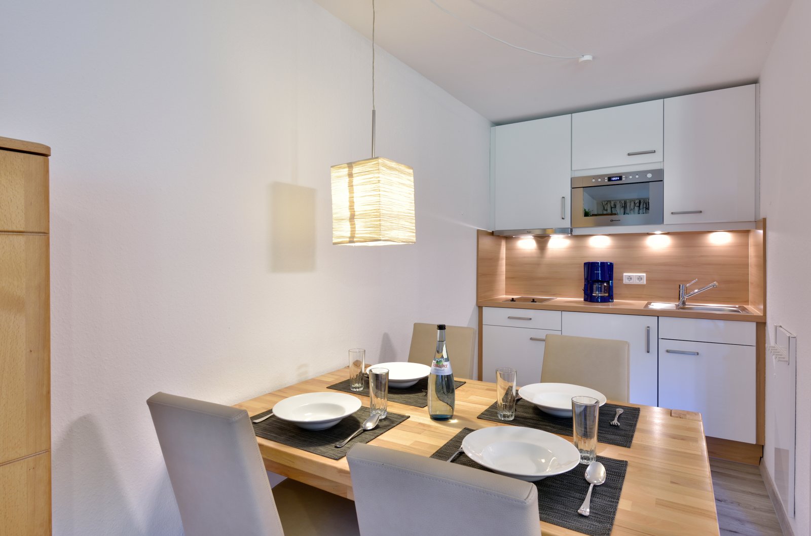 Moderne Küchenzeile in der Ferienwohnung des Die Gams Hotel Resort in Bad Hindelang mit gemütlichem Essbereich, stilvoll gedecktem Tisch und warmem Lichtambiente.