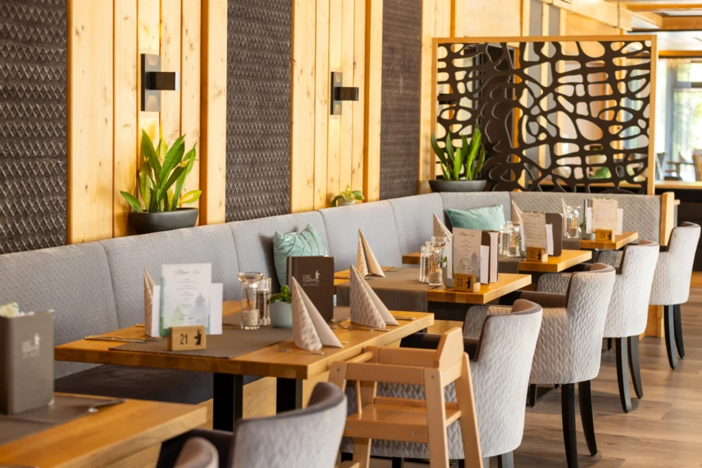 Modern and cozy restaurant at the Die Gams Hotel Resort in Bad Hindelang with upholstered benches, stylish table decorations, and child-friendly facilities.