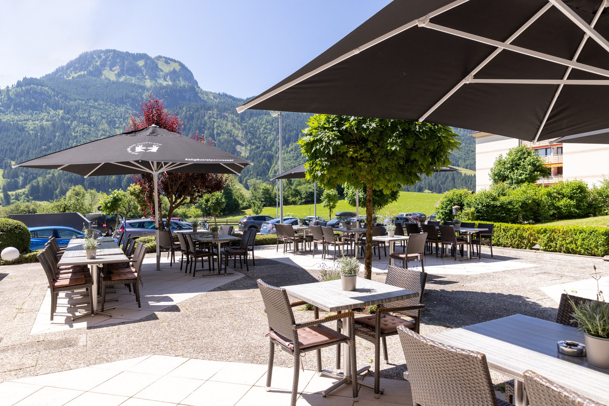 Sonnenterrasse des Die Gams Hotel Resort in Bad Hindelang mit modernen Sitzgruppen, großen Sonnenschirmen und herrlichem Blick auf die Allgäuer Berge.