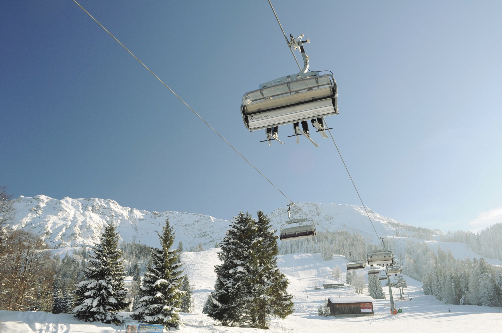 Sessellift der Iselerbahn in Bad Hindelang im Allgäu bei strahlendem Winterwetter mit Blick auf verschneite Pisten und Alpenpanorama.