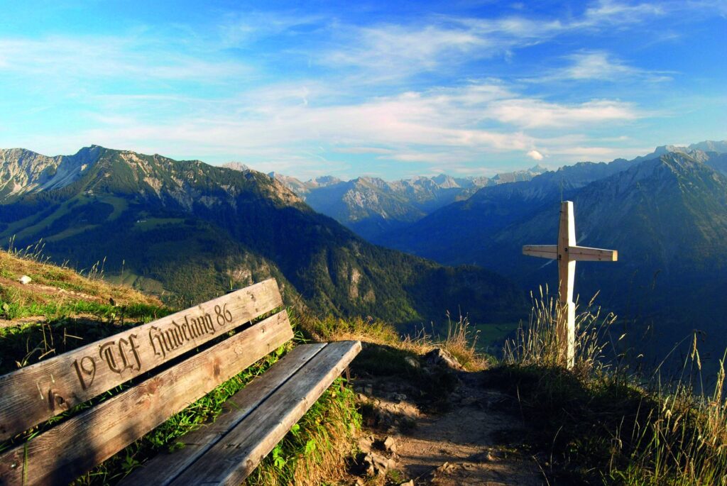 Gipfelkreuz mit Bank und Blick über die Allgäuer Alpen