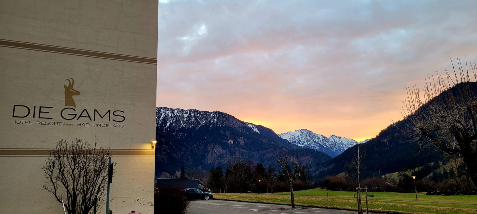 Schriftzug DIE GAMS am Hotel bei Sonnenaufgang mit Blick auf die Allgäuer Berge
