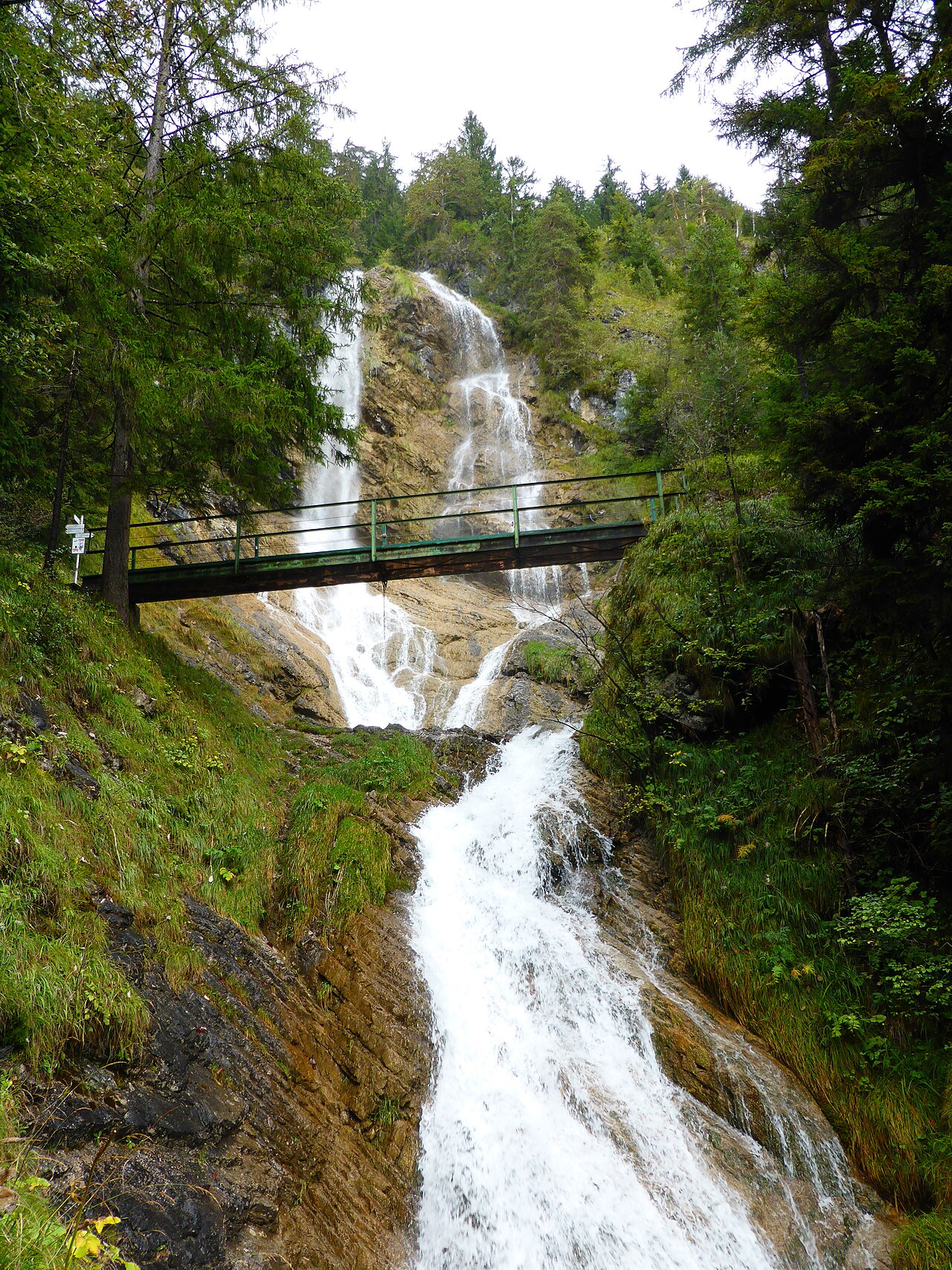 Holzbrücke des Wanderwegs über den Zipfelsbach-Wasserfall in Hinterstein, umgeben von Wald