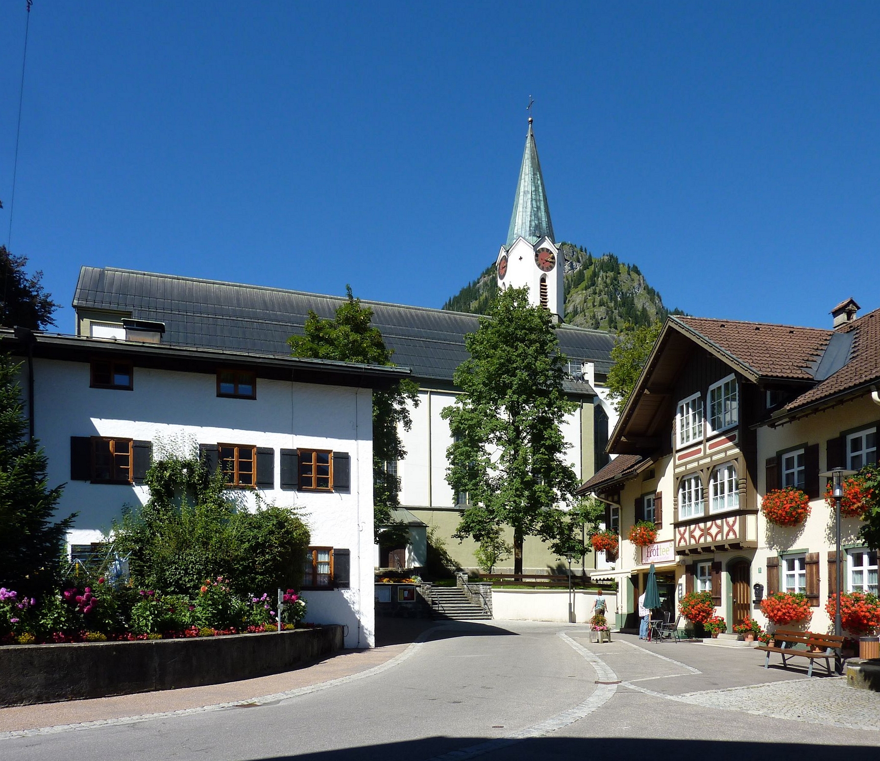 Marktstraße in Bad Hindelang mit Geschäftshäusern und dem Turm der Pfarrkirche