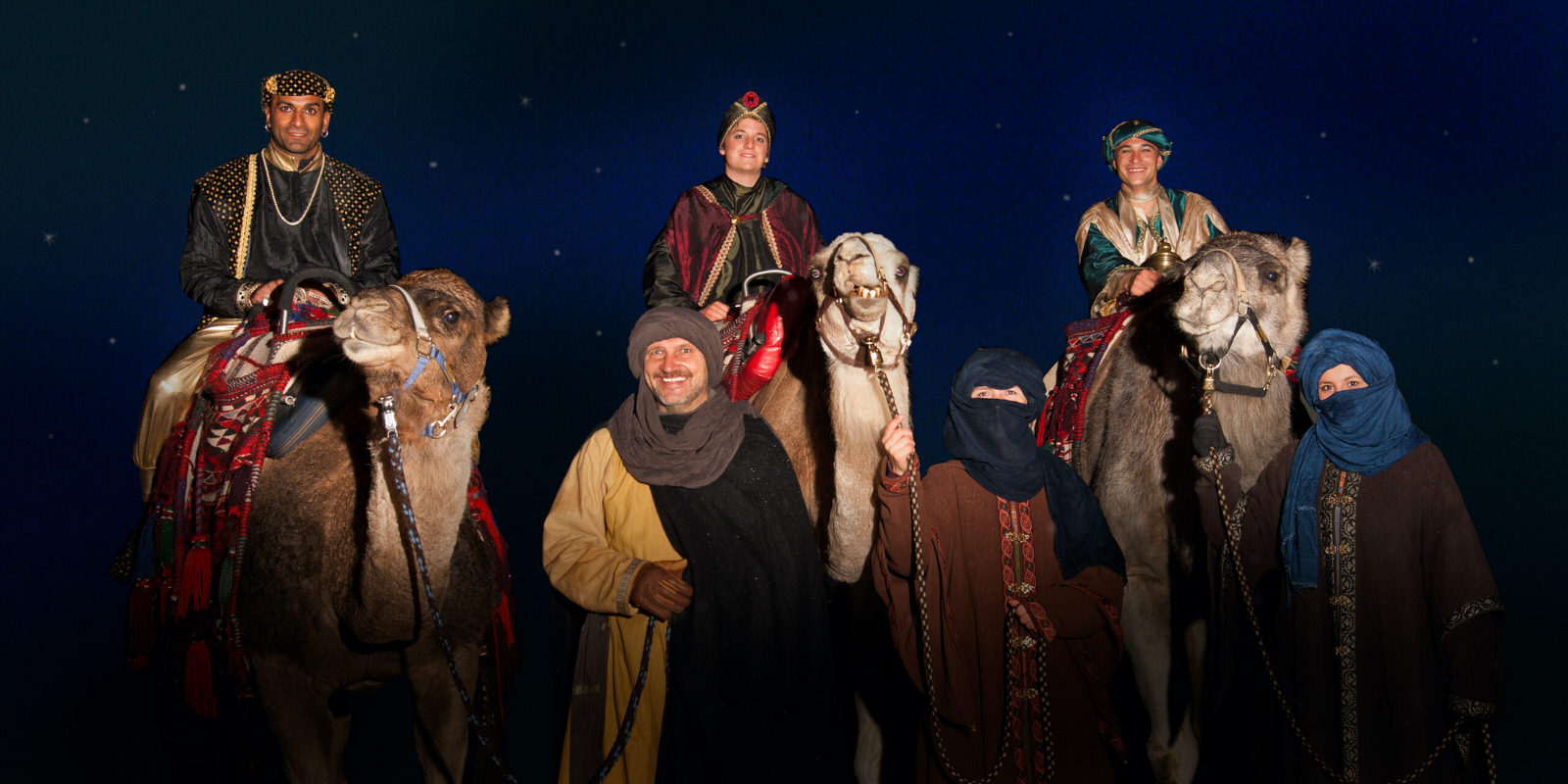 Heilige Drei Könige auf Kamelen beim Weihnachtsumzug vor dunkelblauem Abendhimmel