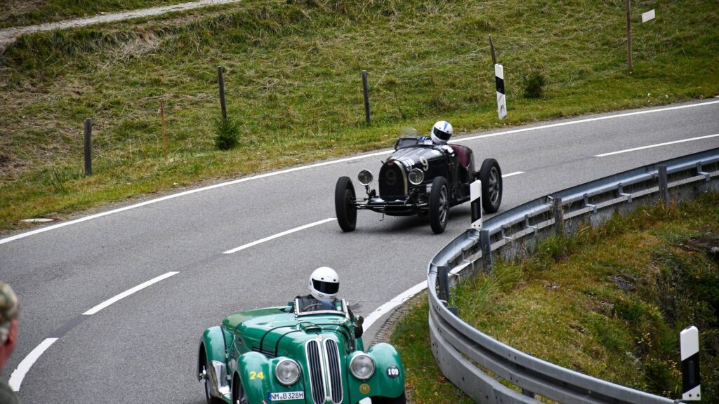 Zwei Vorkriegs-Rennwagen fahren beim Jochpass Memorial durch eine Kehre der Jochstraße bei Bad Hindelang