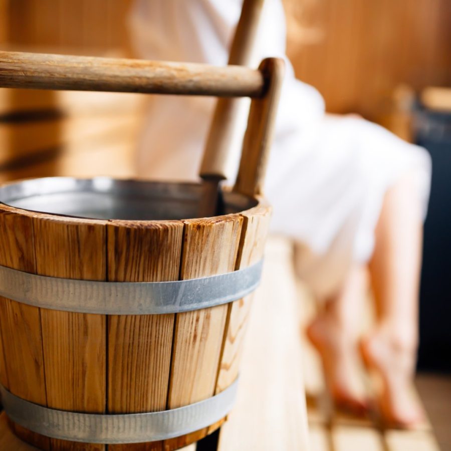 Detailaufnahme aus dem Saunabereich des Die Gams Hotel Resort in Bad Hindelang mit traditionellem Aufgusskübel aus Holz und entspannter Wellnessatmosphäre.